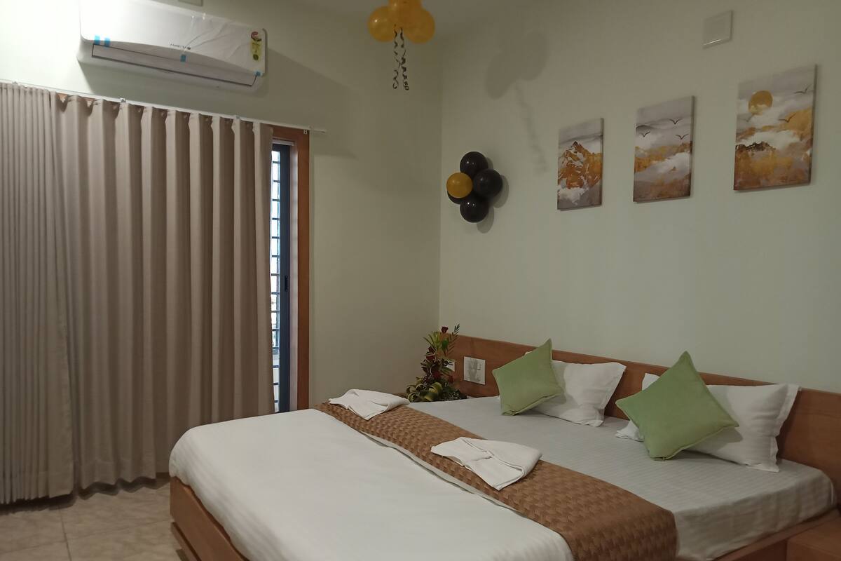 A hotel room with a bed, curtains, an air conditioning unit, and wall art.