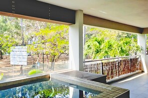 A modern indoor pool area with glass walls, a metal pool, and a view of trees and a signboard. - Element Bay 5 - Three Bedroom Apartment, Sleeps 6 (Cap Malheureux)