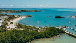 Vue aérienne d’une zone côtière avec une plage, des bateaux et une jetée.