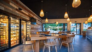 Un restaurant doté d’un long comptoir en bois, de plusieurs lampes suspendues et d’un présentoir à vin situé sur le côté gauche.