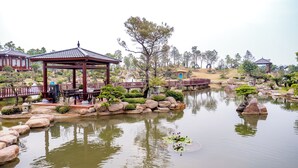 Ein traditioneller japanischer Garten mit einem hölzernen Pavillon, Felsformationen und einem Teich.