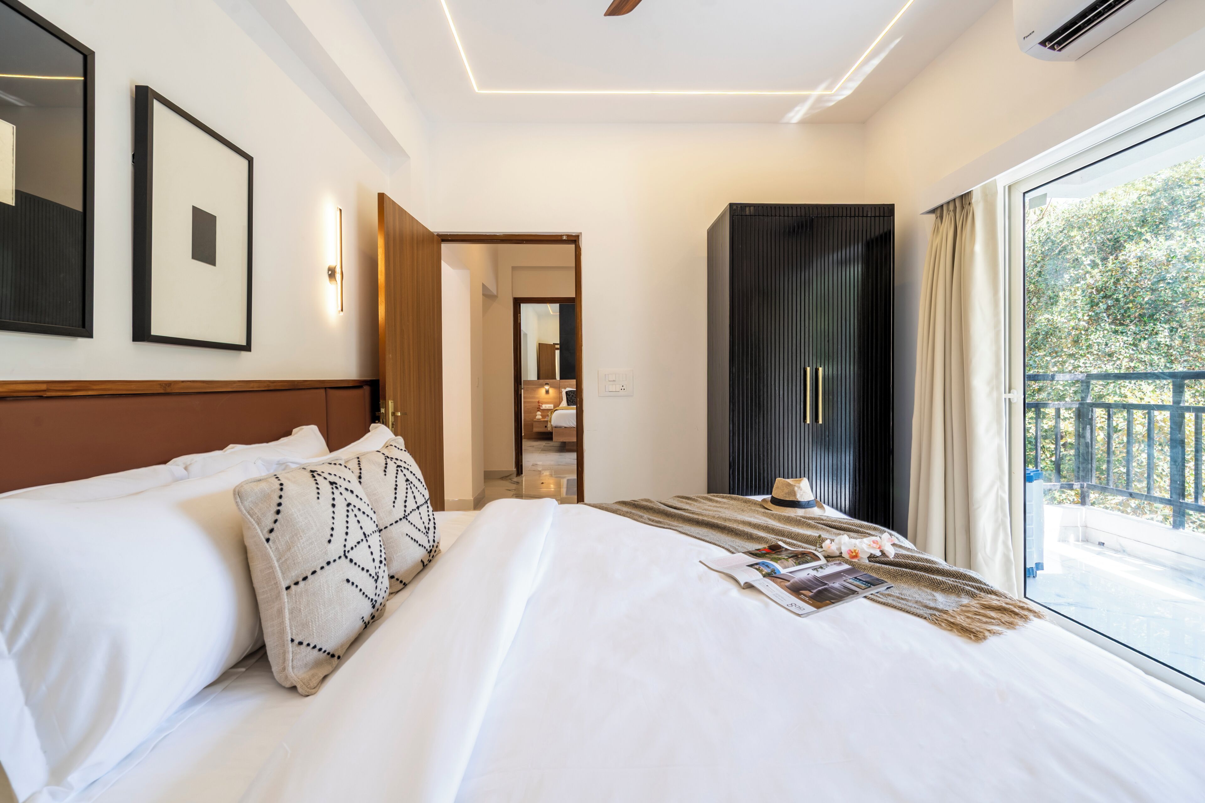 A hotel room with a large bed, a view of the outdoors, and a door leading to a bathroom.
