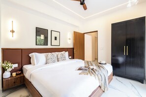 Ein modernes Schlafzimmer mit einem großen Bett, Nachttischen, einem Kleiderschrank und einem Deckenventilator.