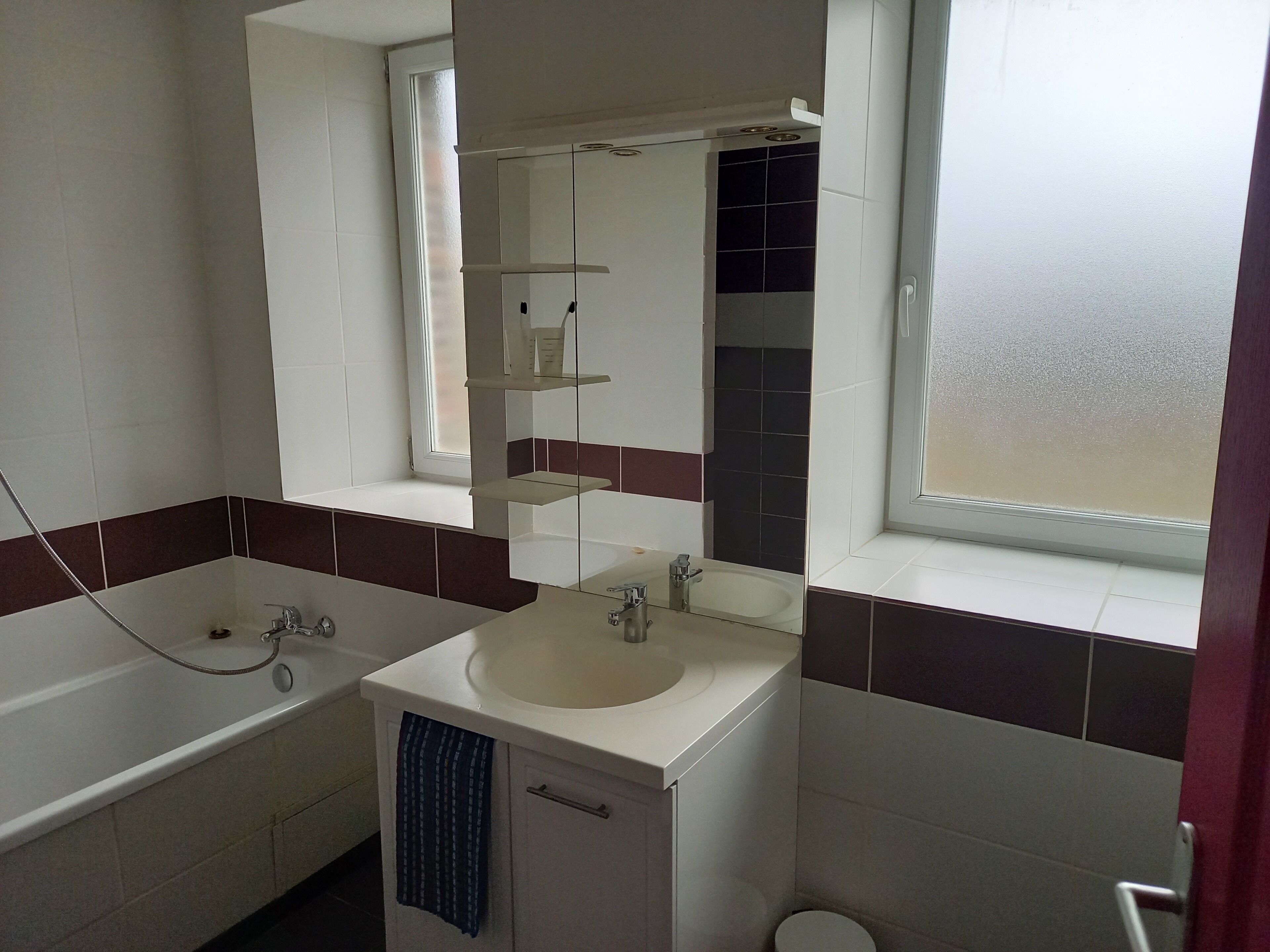 Een badkamer met een bad, een wastafel, een spiegel en een raam.