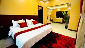 Camera d'albergo con un letto grande, un tappeto rosso e vista su un'area ristorazione.