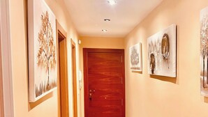 Ein Korridor mit Holzboden, einer Holztür am Ende und Kunstwerken an den Wänden.
