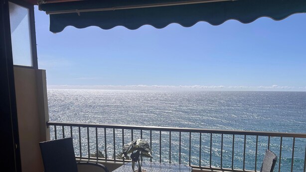 Ein Balkon mit Meerblick, einem Metallgeländer und einem Stuhl.