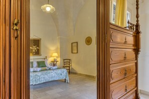 Quarto com cama, cômoda, cadeira e abajur.