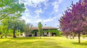Uma casa com telhado de telhas, cercada por um gramado bem cuidado e árvores.