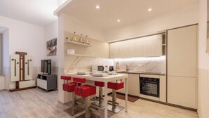 A modern kitchen with a dining area, built-in appliances, and a small TV. - SANTA MARTA by Design Studio (Bellano)