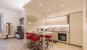 A modern kitchen with a dining area, built-in appliances, and a small TV. - SANTA MARTA by Design Studio (Bellano)