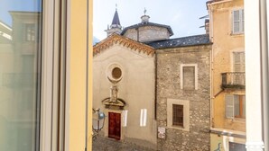 A narrow street with a building featuring a round window and a red door. - SANTA MARTA by Design Studio (Bellano)