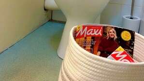 Inodoro con un portalrevistas que contiene una revista.