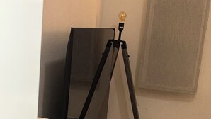 Una habitación con un trípode, un proyector y un felpudo blanco y mullido.