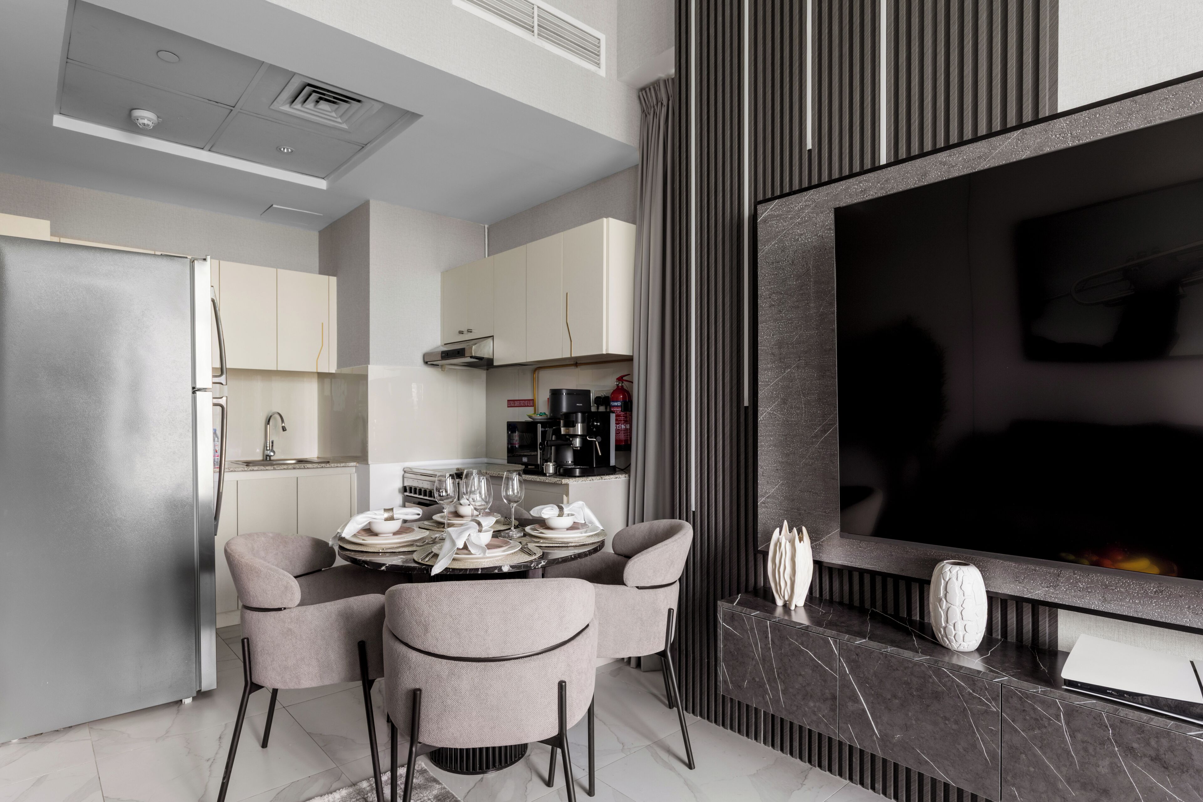A modern kitchen with a dining area, a built-in oven, and a flat-screen TV.