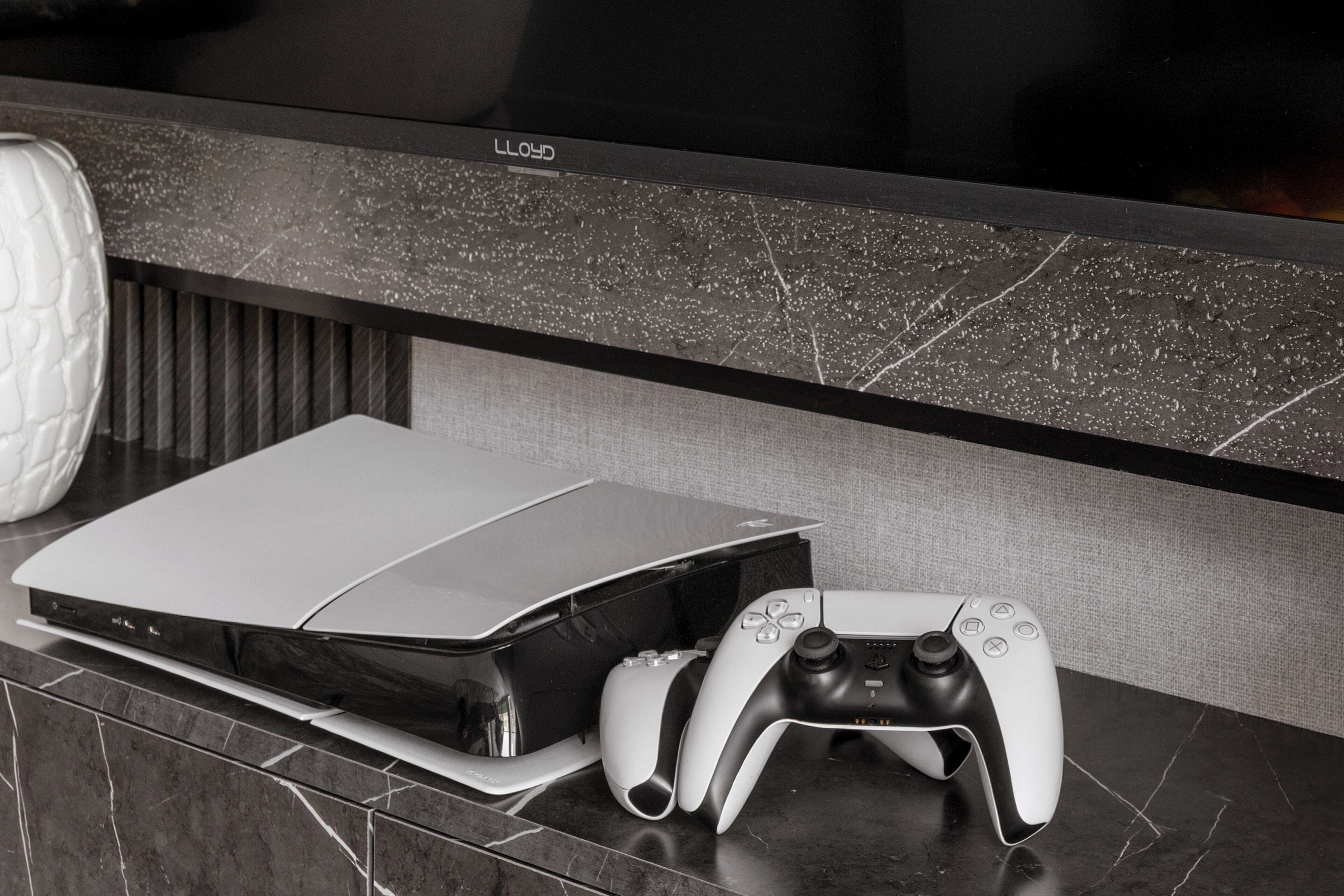 A gaming console and controller on a marble countertop.