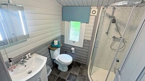 Ein Badezimmer mit Waschbecken, Toilette, Dusche und einem Fenster mit Jalousien.