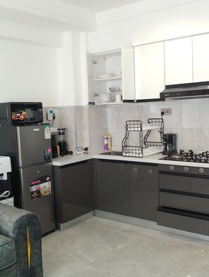 A modern kitchen with a refrigerator, microwave, stove, and cabinets. - Cozy 1-bedroom apartment in serene Nairobi with fitness room Lavington-Kilimani (Nairobi)