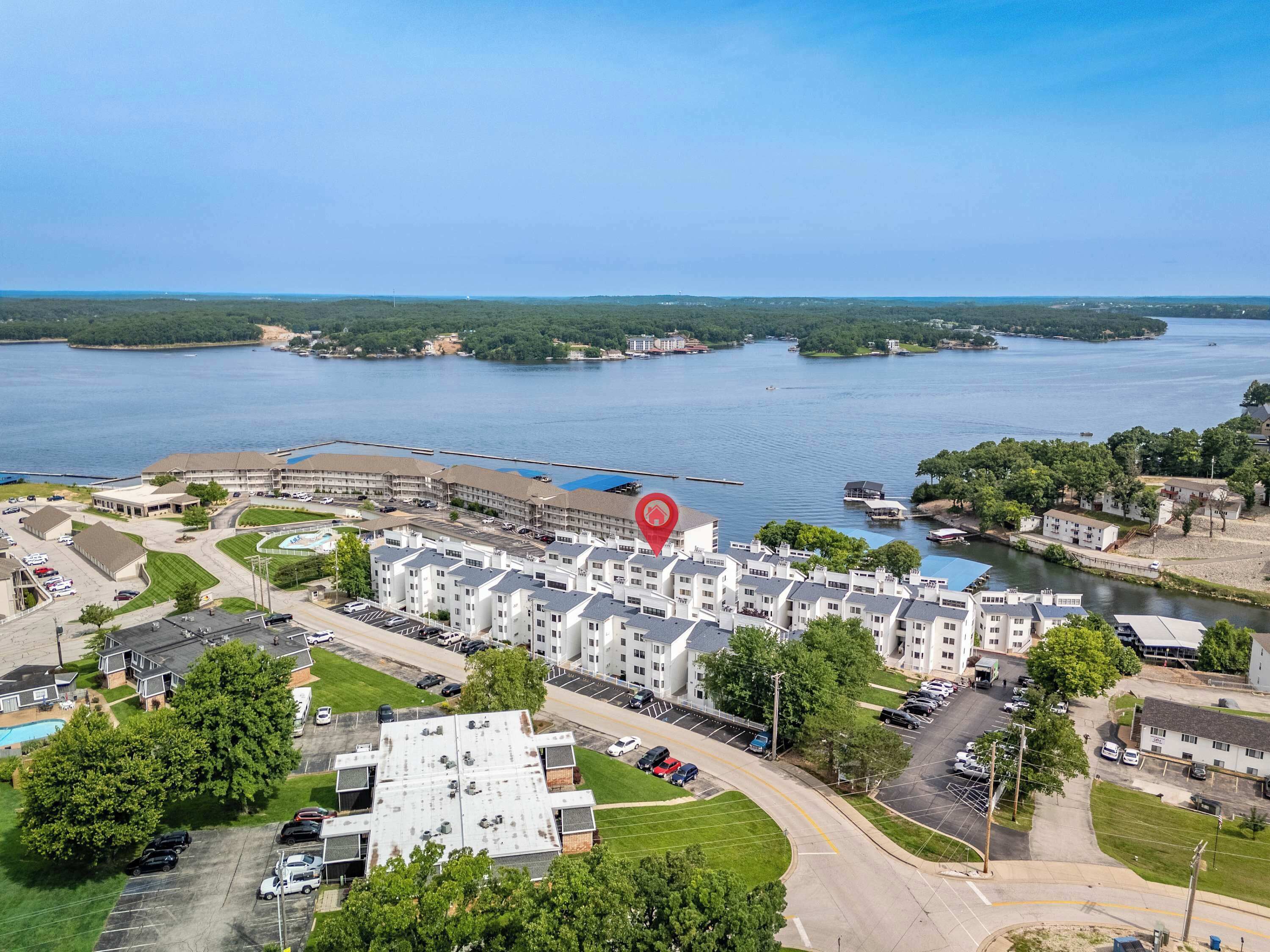 A residential area with apartment buildings, a parking lot, and a body of water in the background.