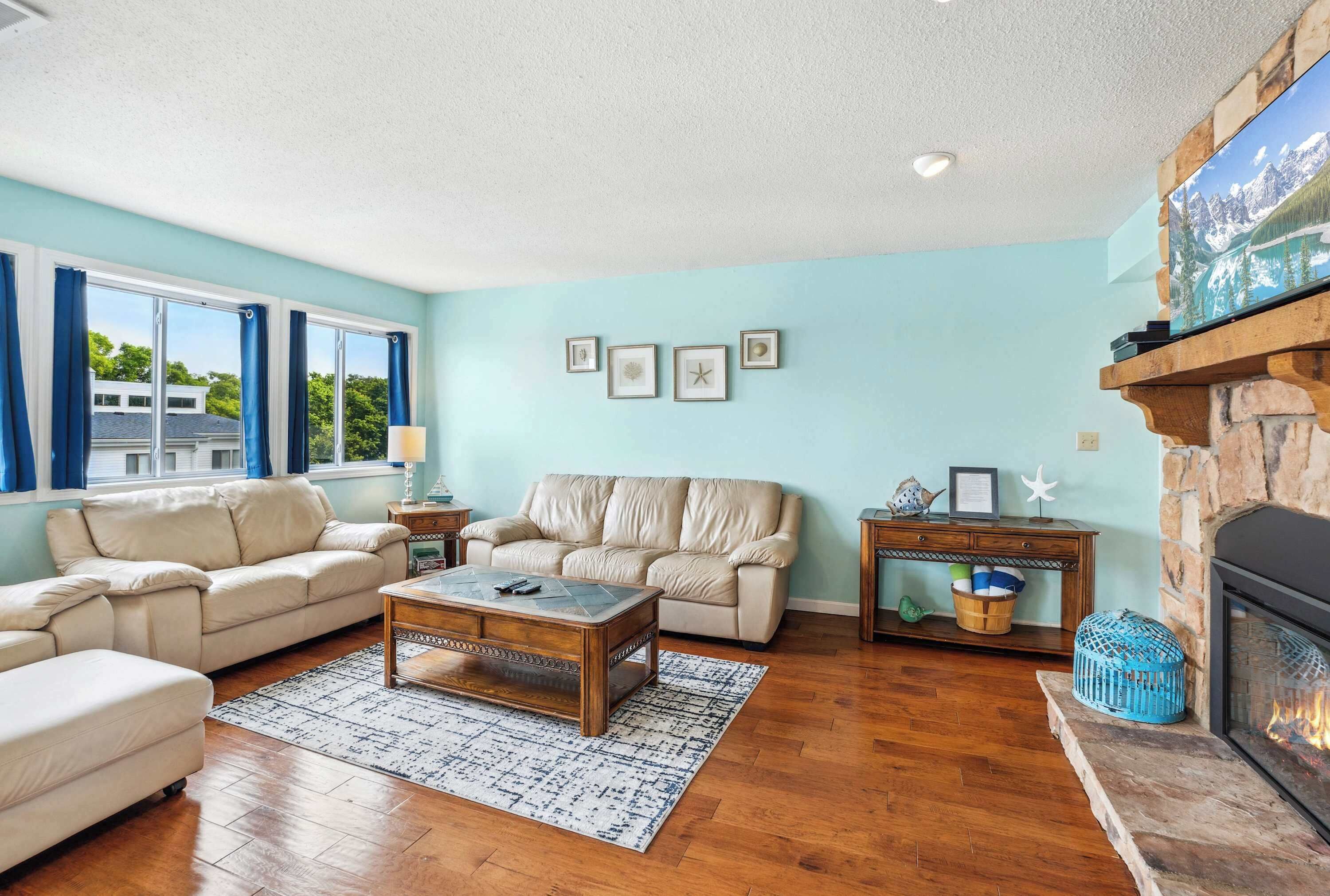 A living room with a beige sofa, a wooden coffee table, a fireplace, and framed pictures on the wall.