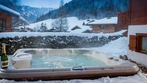 A hot tub in a snowy outdoor setting with mountains in the background. - Simply Morzine - Apartment des Montagnes (Les Gets)