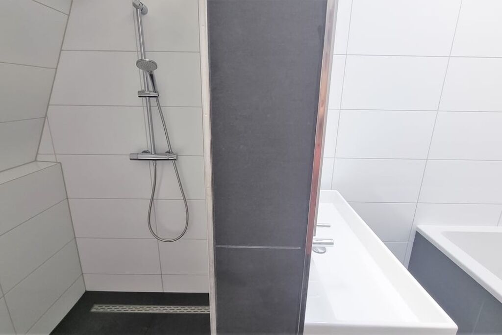 Une salle de bain avec une douche, une baignoire et un carrelage au sol.