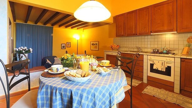 A dining area with a table set for breakfast, wooden cabinets, and a tiled backsplash.