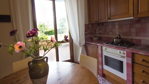 A kitchen with wooden cabinets, a stove, and a table with a vase of flowers.