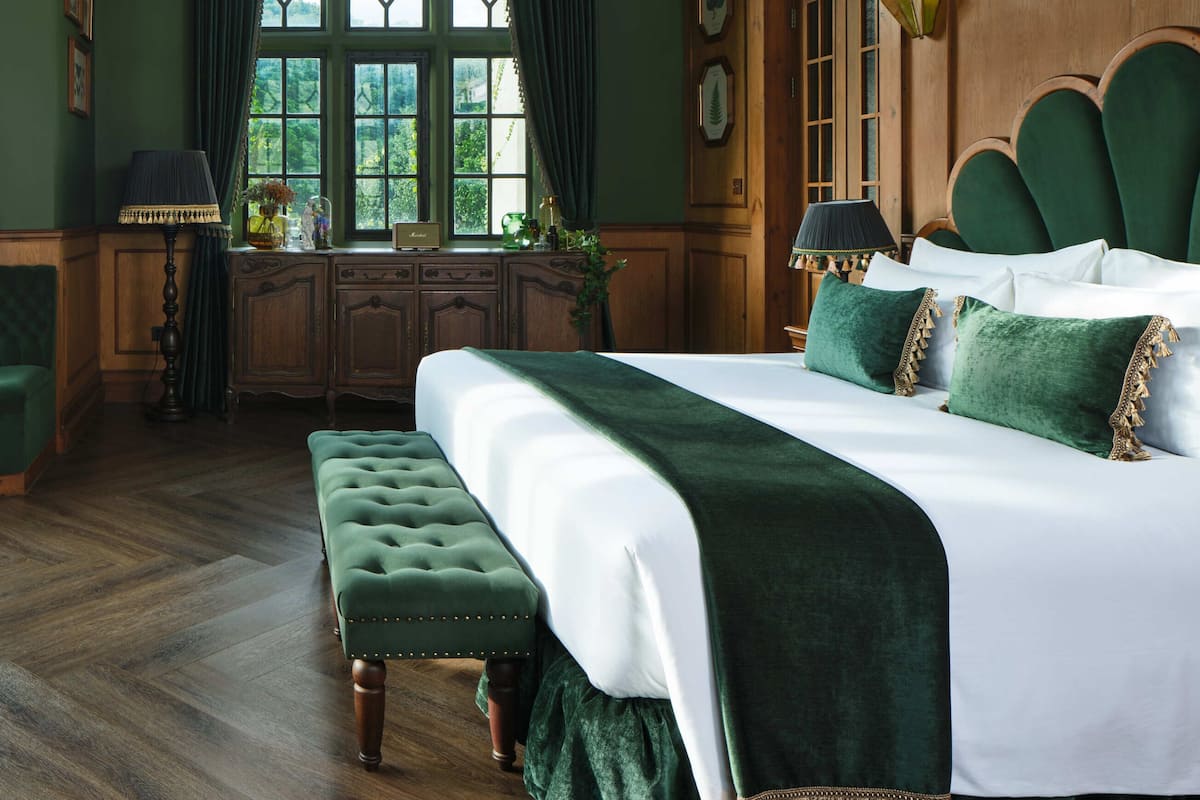 Quarto com uma cama grande, uma escrivaninha de madeira e uma janela com cortinas.
