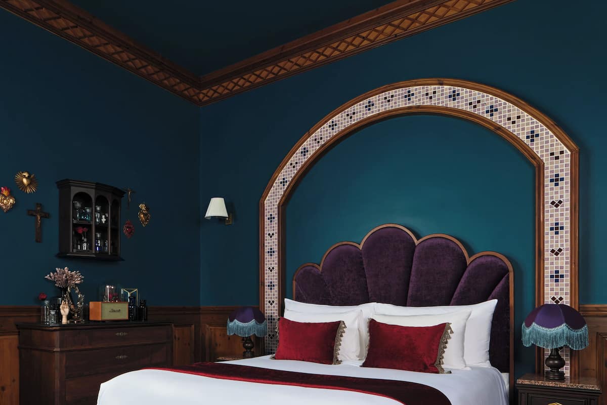 Quarto com uma cama grande, um banco, uma mesa de cabeceira e um armário.