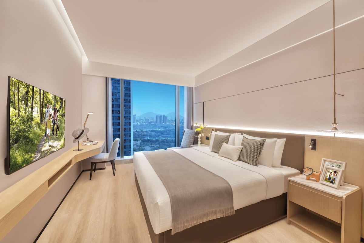 Una habitación de hotel moderna con una cama grande, un escritorio y vistas a la ciudad.