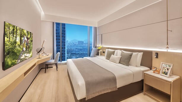 A modern hotel room with a large bed, a desk, and a view of the city.