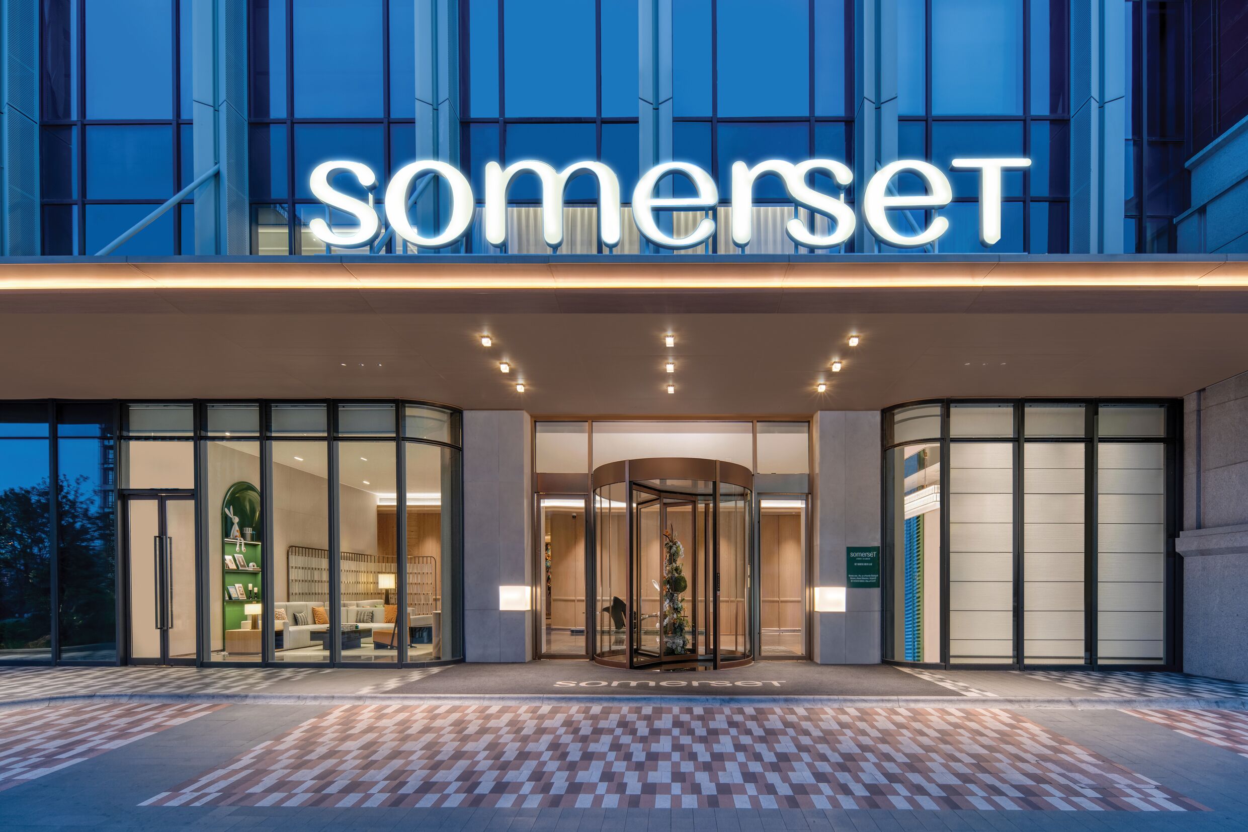 A hotel entrance with a revolving door and a glass facade.