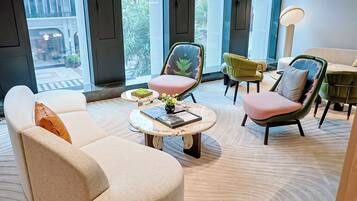 A modern interior with a sofa, chairs, a round coffee table, and a view of the outside.