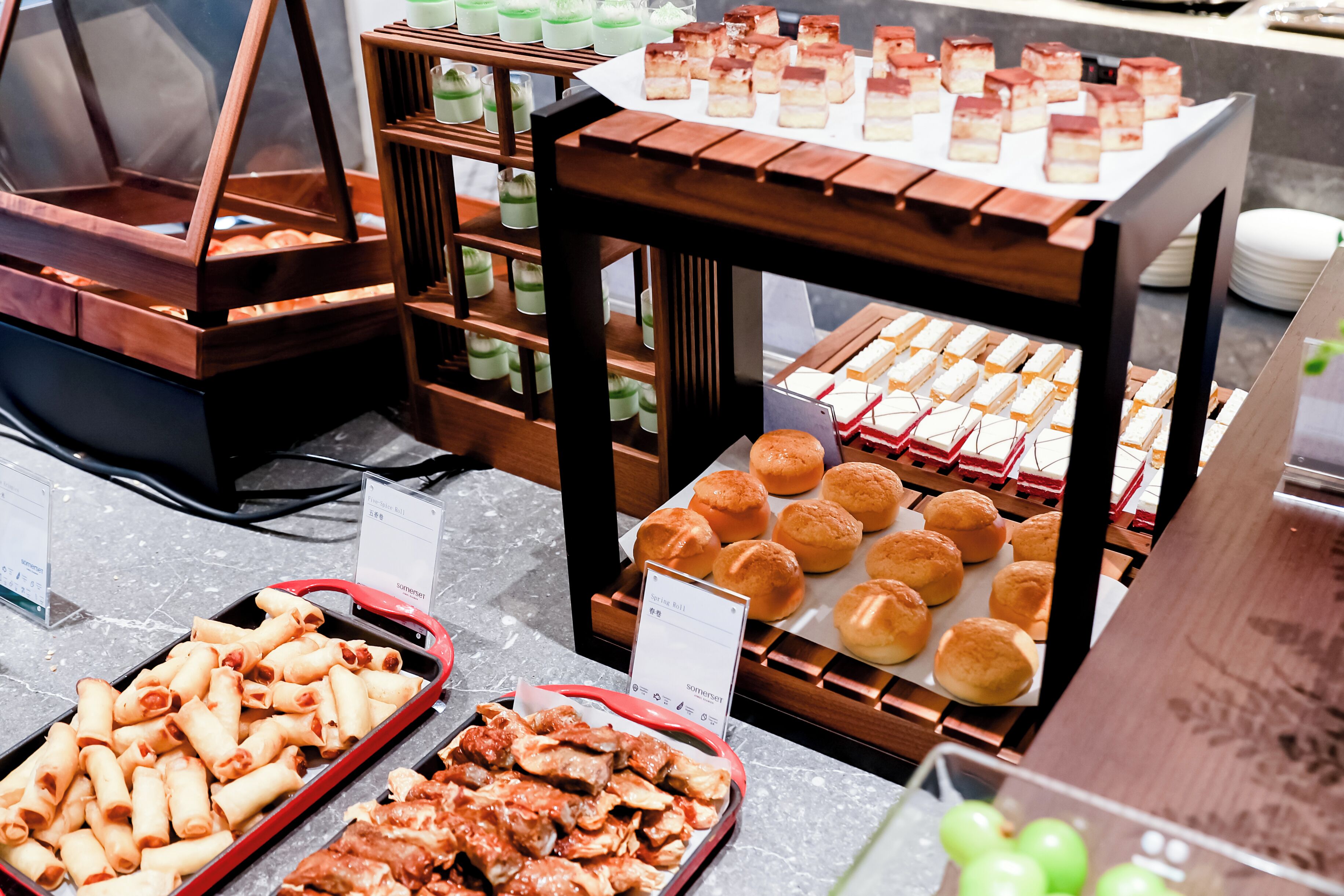 A buffet with various food items including pastries, rolls, and desserts.