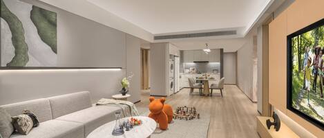 A modern living room with a sofa, coffee table, bear-shaped toy, and a TV.