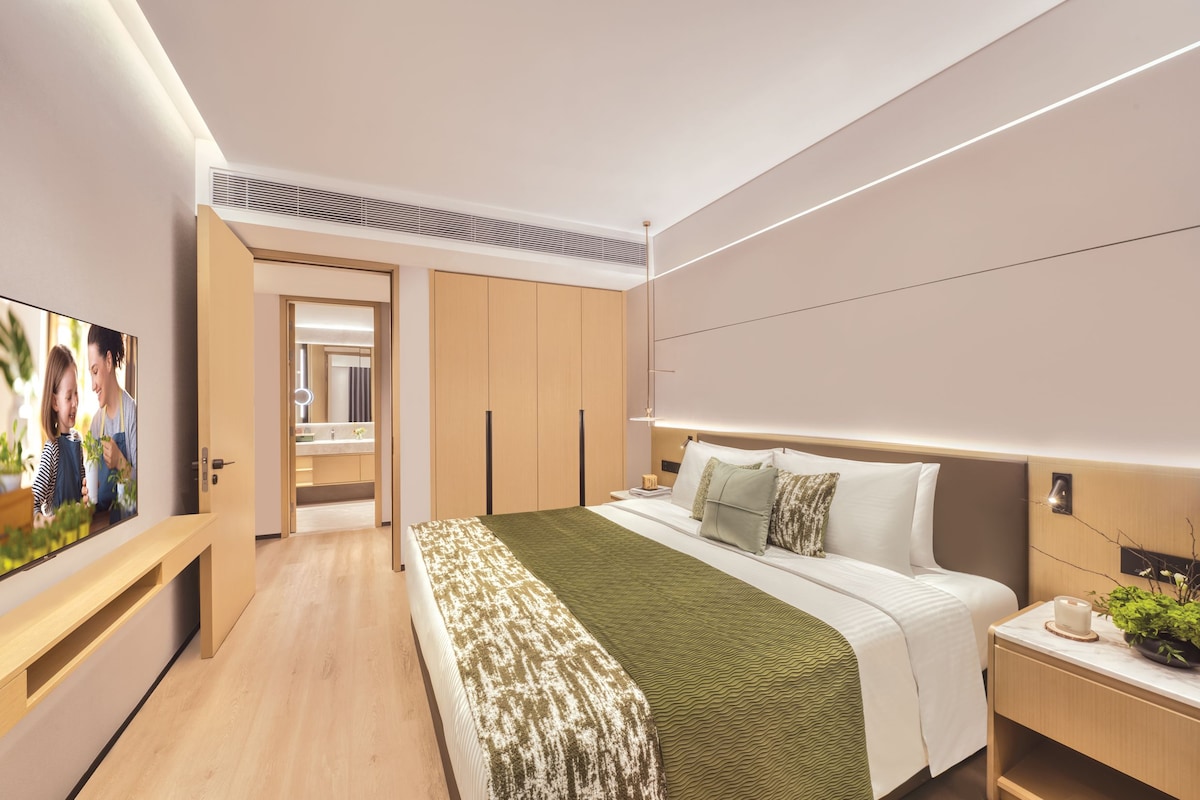 Una habitación de hotel moderna con cama, mesita de noche y televisor.