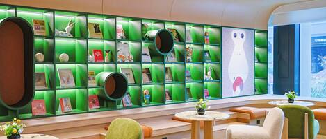 Un interior moderno con estanterías verdes, asientos mullidos y una gran composición mural.