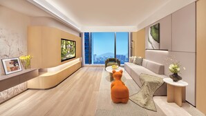 A modern living room with a sofa, a coffee table, a TV, and a large window with a city view.