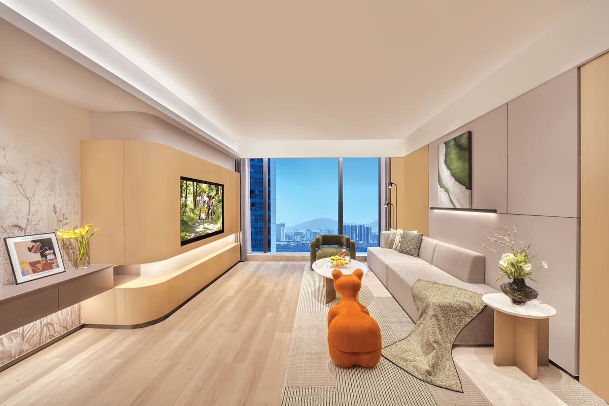 A modern living room with a sofa, a coffee table, a TV, and a large window with a city view.