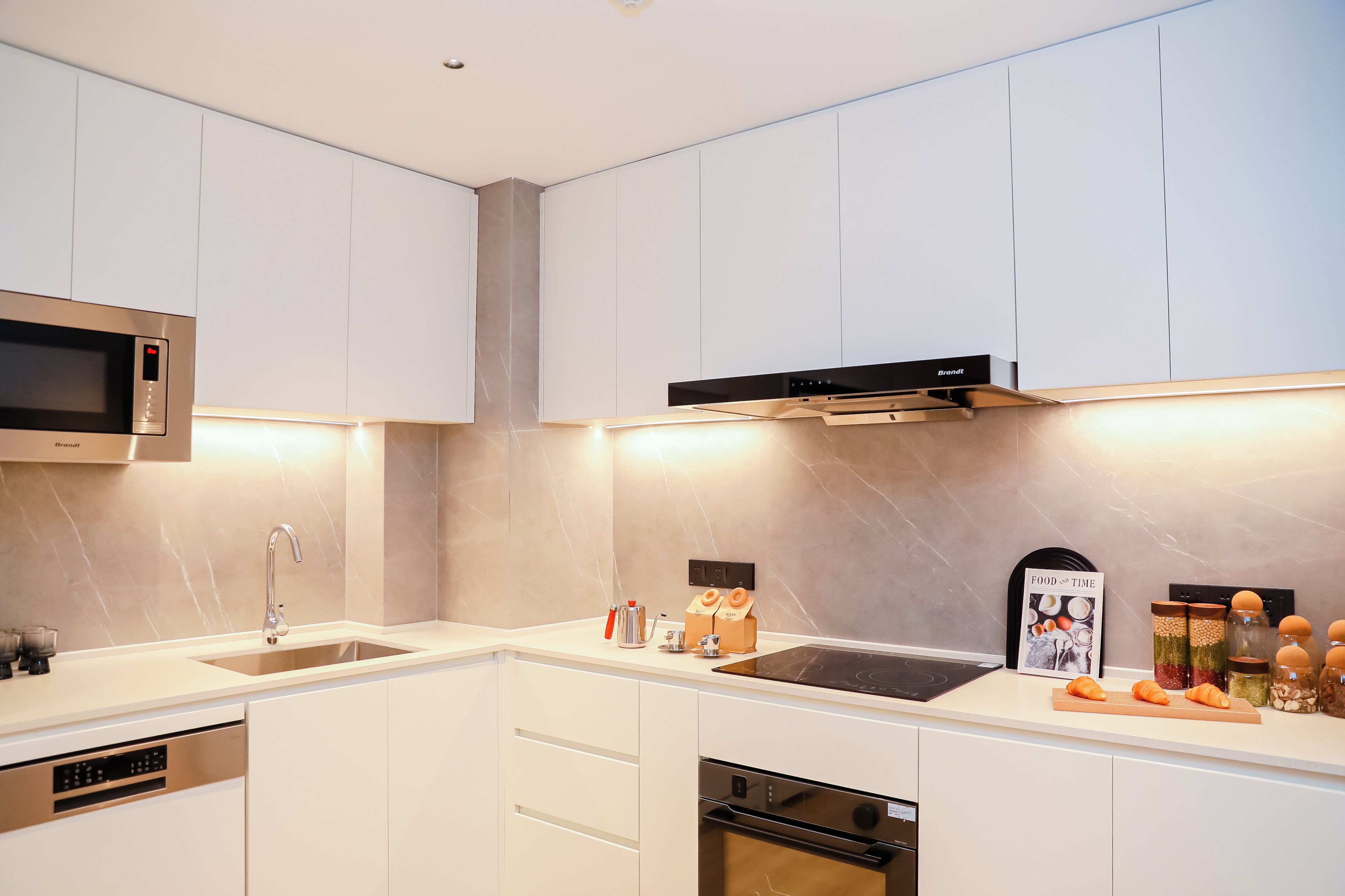 A modern kitchen with white cabinetry, stainless steel appliances, and a built-in microwave.