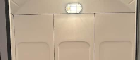 A restroom with three urinals, a floor drain, and a light fixture above the urinals.