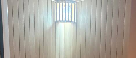 Sala de sauna com ripas de madeira, um banco e um balde de madeira.