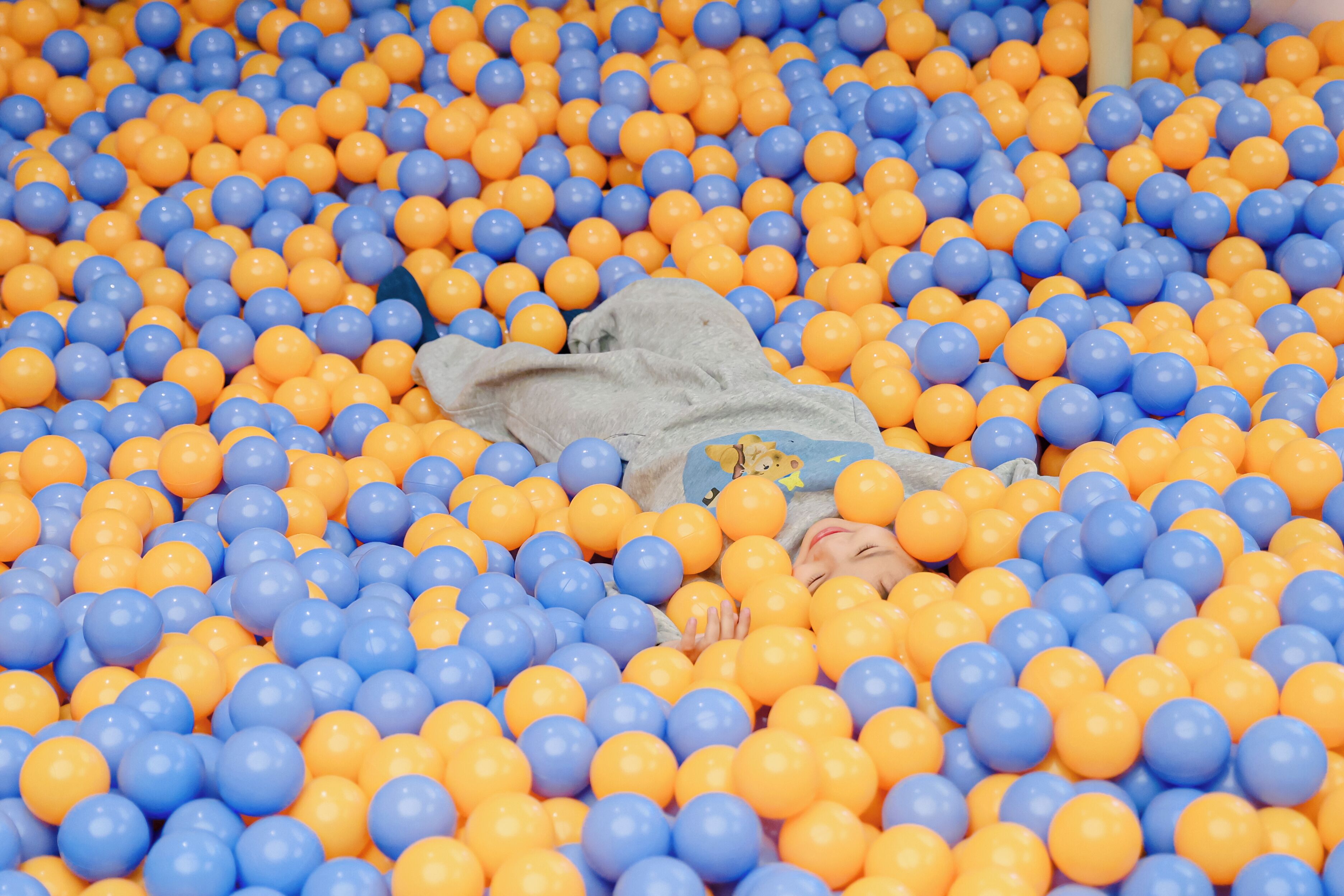 Una piscina de pelotas llena de pelotas azules y anaranjadas.