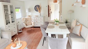 Ein modernes Wohnzimmer mit Esstisch, grauen Stühlen, einem weißen Sofa und einer Vitrine.