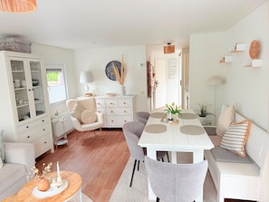 A modern living room with a dining table, grey chairs, a white sofa, and a cabinet with glass doors. - Chalet 229 (4 persons) (Petten)