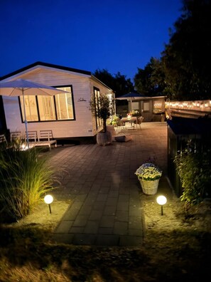 A residential property with a paved patio, outdoor seating, and a small garden area. - Chalet 229 (4 persons) (Petten)