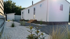 Ein Bungalow mit einer Veranda, einer kleinen angebauten Garage und einem Schotterweg.