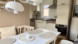 Eine moderne Küche mit weißen Schränken, einem Esstisch mit Platzsets und hängenden Pendelleuchten.