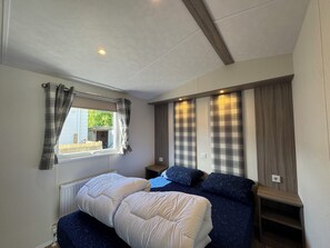 A bedroom with a bed, a window with curtains, a radiator, and a wall with a built-in shelf. - J 041 New chalet! (more photos to follow) (Petten)